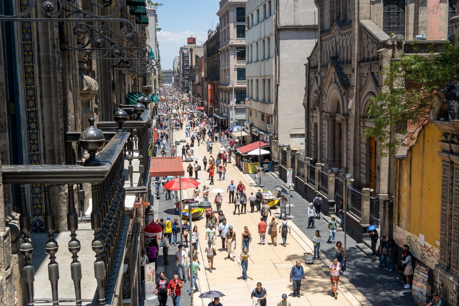 Scène de rue animée sur la Calle Madero avec des piétons et une architecture historique à Mexico, un après-midi d'été.