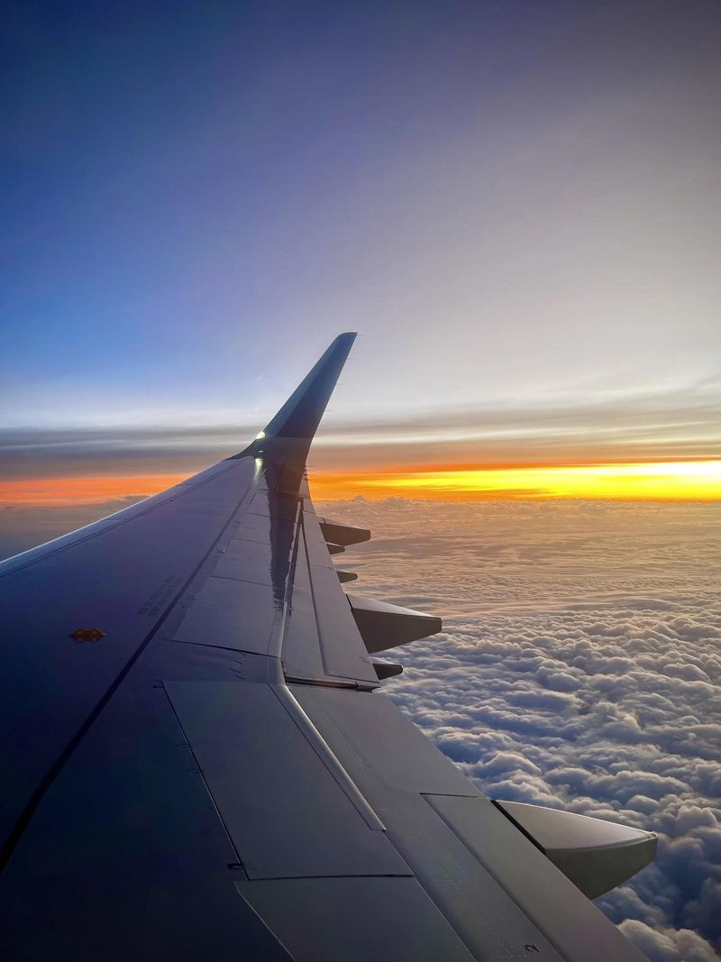 Aile d'avion au-dessus des nuages au coucher du soleil